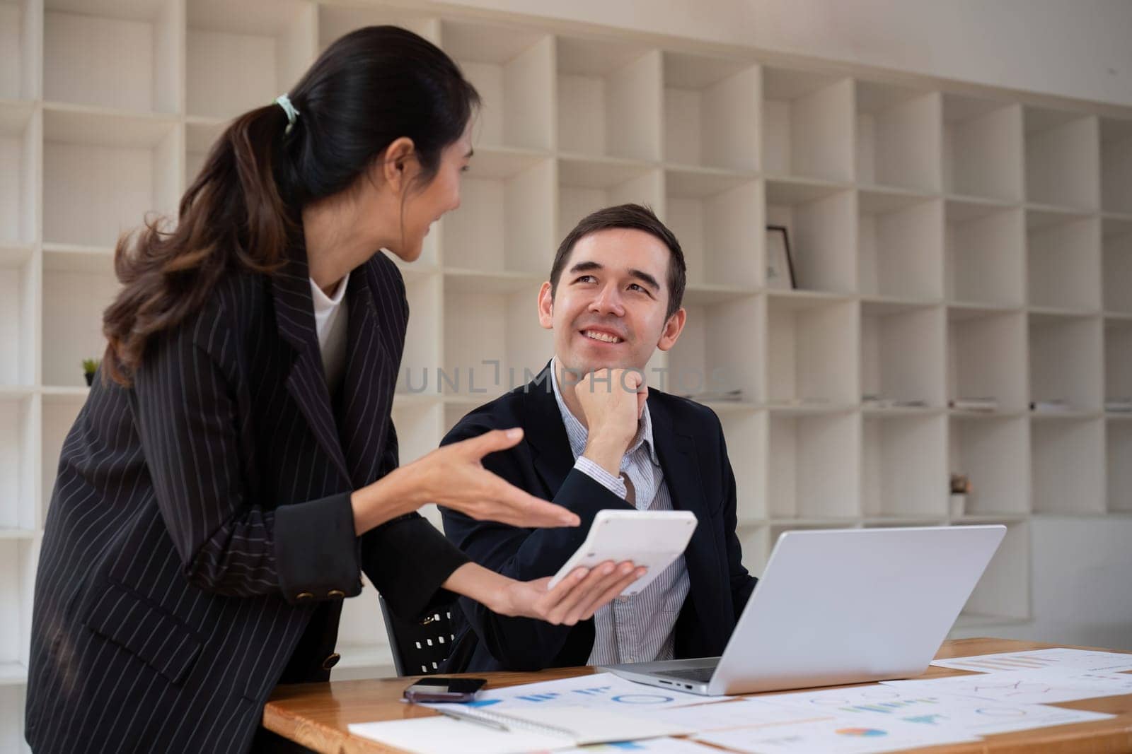 Two businessmen discussing project at the office room Businessman discusses project planning with colleagues in modern workplace while having discussion and advice on financial data report..