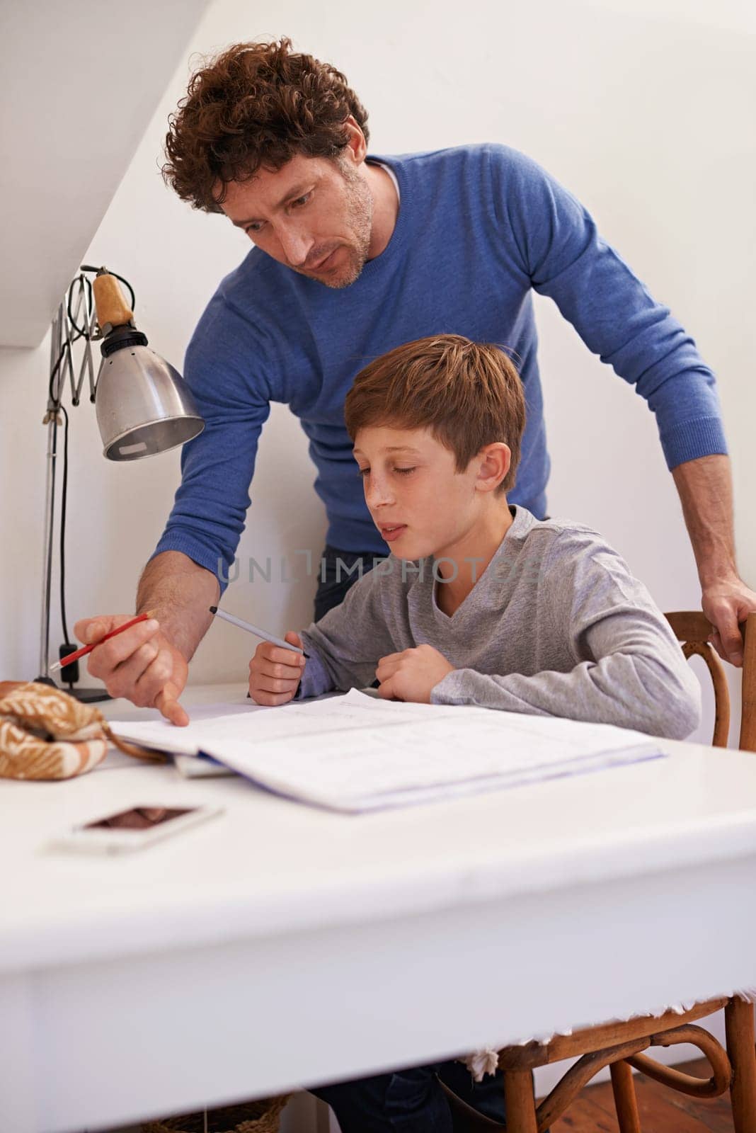 Teen, dad and help with studying in home, student and support for assignment or project. Daddy, boy and schoolwork on weekend in bedroom, education and assistance or guidance for learning by desk.