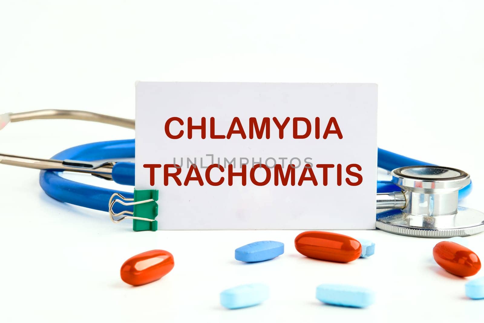 Chlamydia trachomatis on a white business card on a white background next to a stethoscope and pills, vitamins