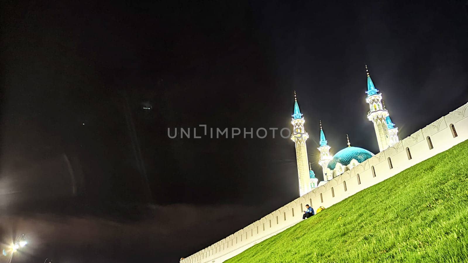 Beautiful white mosque with minarets against dark cloudy sky in night or evening. Ramadan Holiday