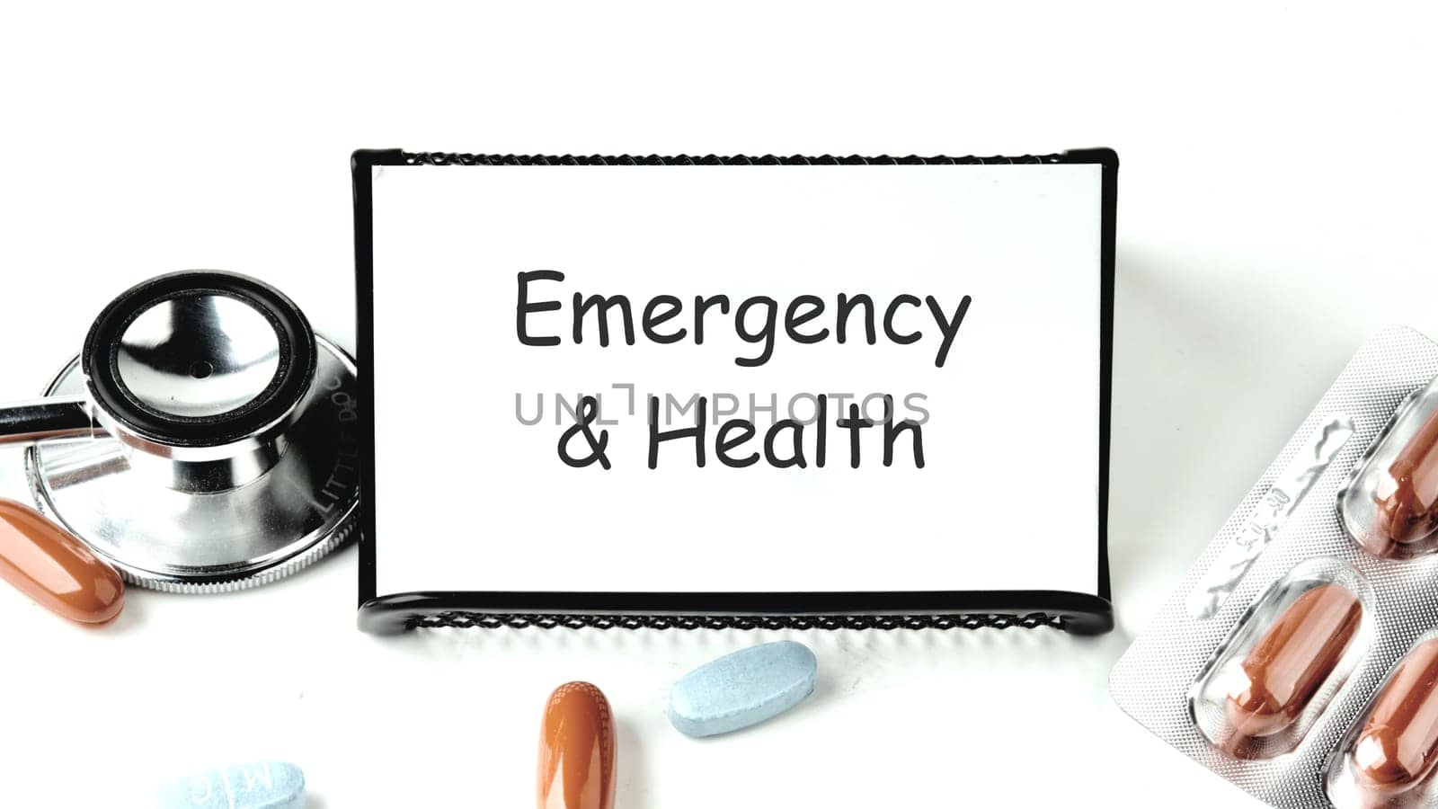 Medical concept. Emergency and Health text on a business card on a stand on a white background next to pills, medicines