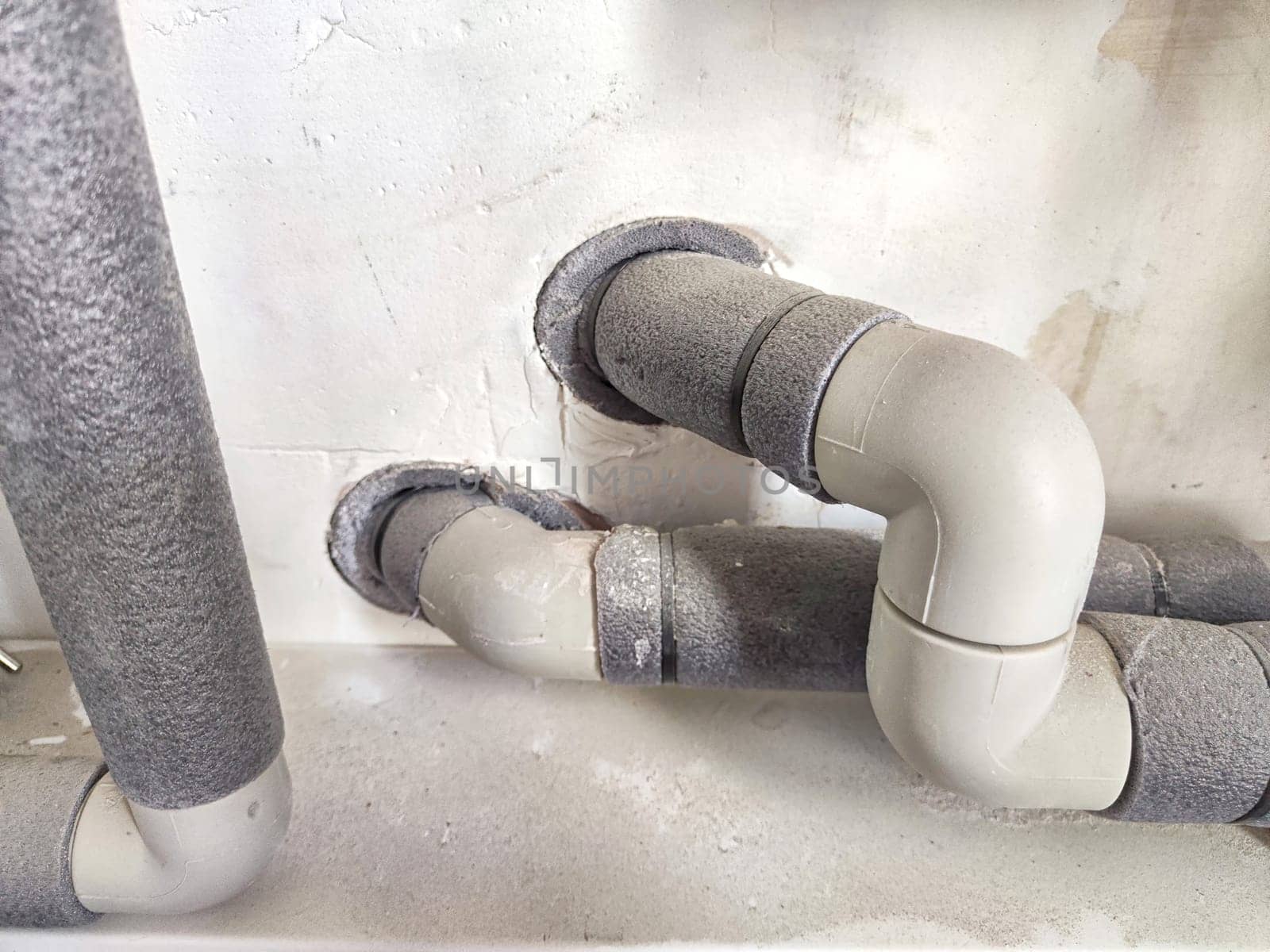 Close-up of insulated plumbing pipes. Insulated Pipes in Public Restroom on the wall