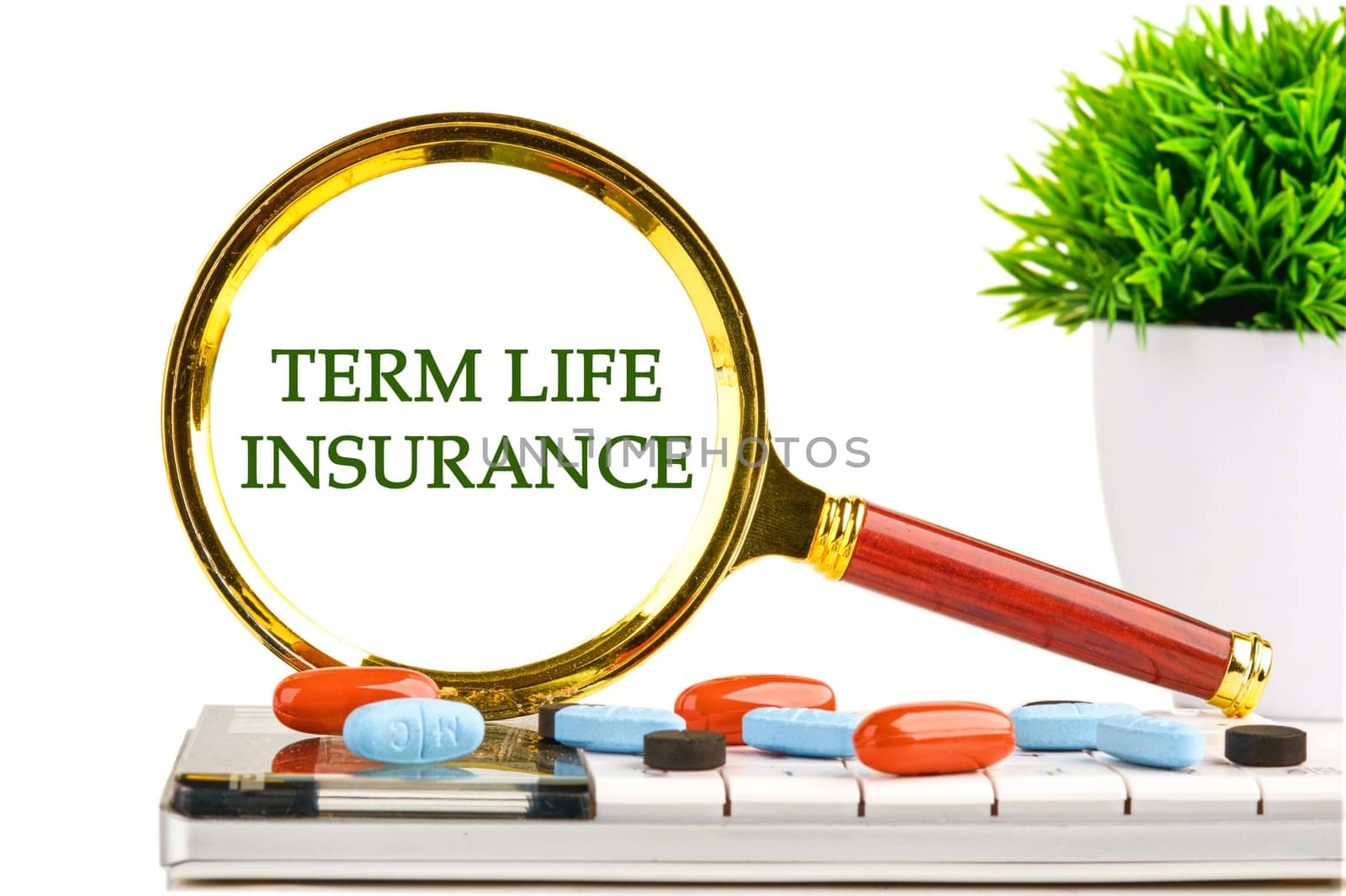 Medical concept. TERM LIFE INSURANCE through a magnifying glass on a white background on a calculator with a green plant and tablets, vitamins