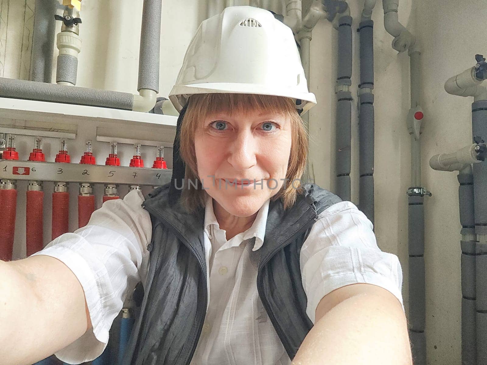 Female middle aged Technician Adjusting Industrial Water Filtration System. Woman services a water filtration unit and posing for photo or selfie