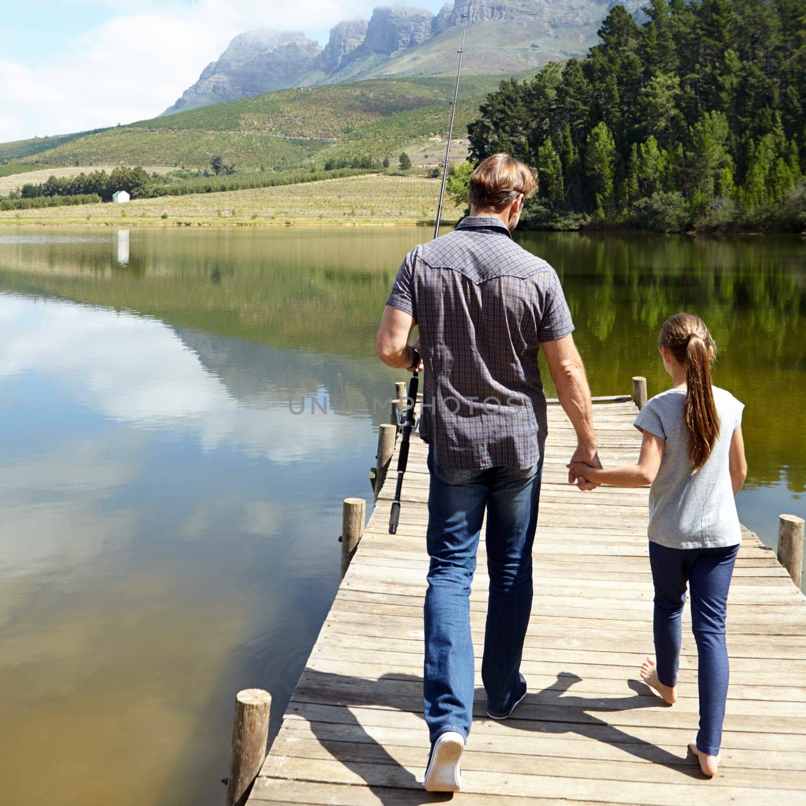 Father, daughter and holding hands by lake for fishing, vacation or summer with walk on jetty. Dad, man and girl child with bonding, connection and outdoor for adventure, learning or holiday by river by YuriArcurs