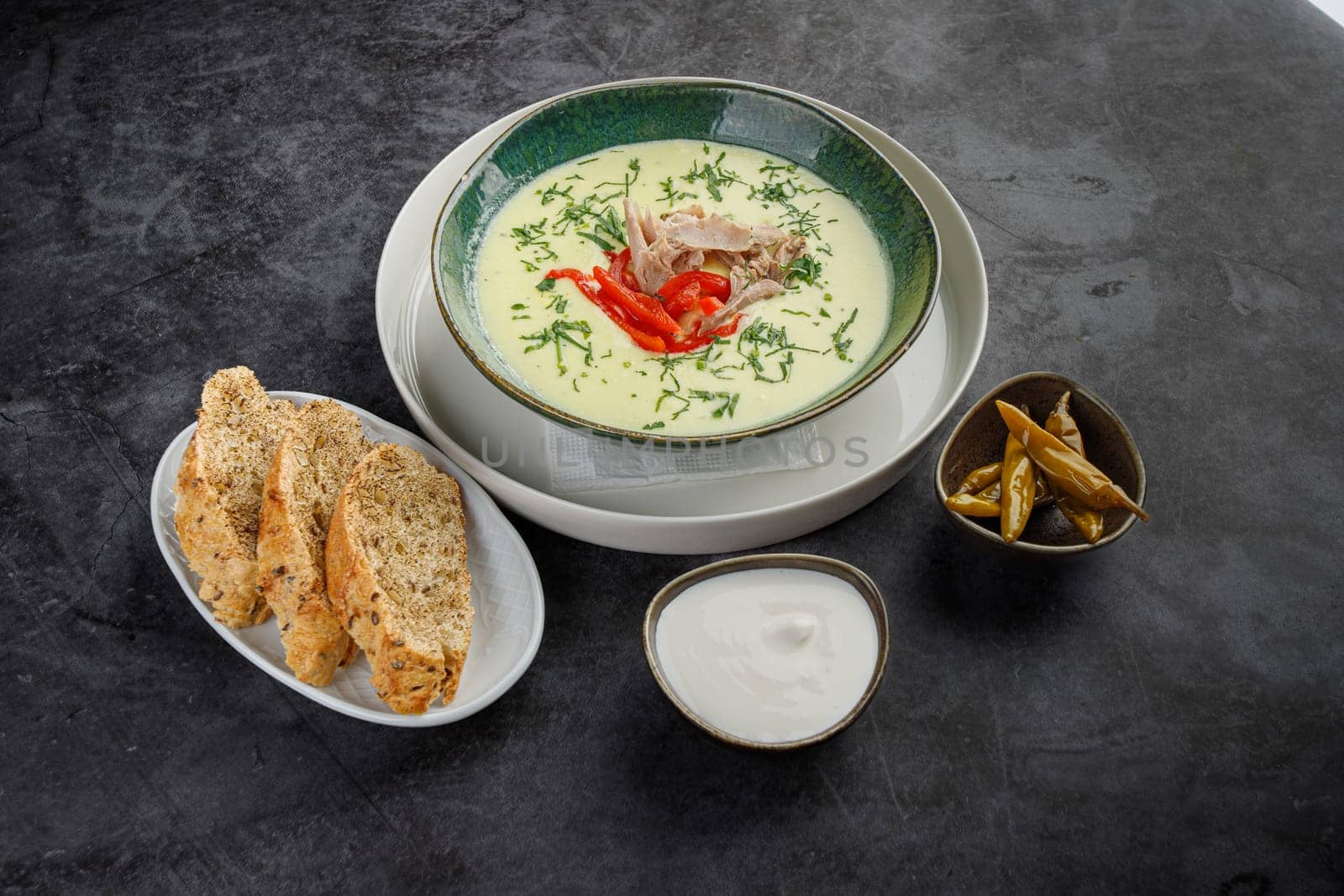 Side view, seasonal cream soup with meat and vegetables on a gray stone background. Restaurant menu