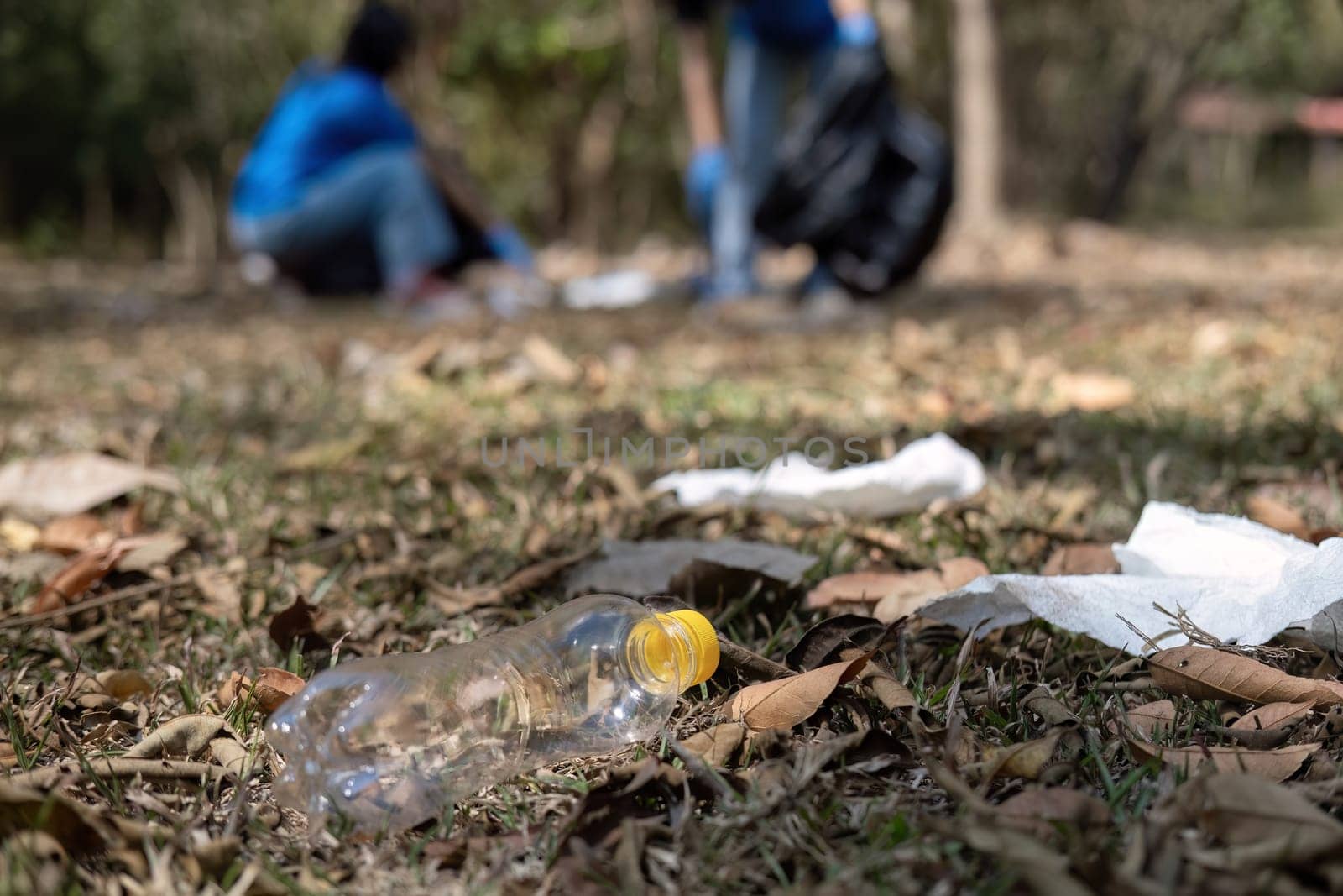 close up view, A group of Asian volunteers collects trash in plastic bags and cleaning areas in the forest to preserve the natural ecosystem. by wichayada