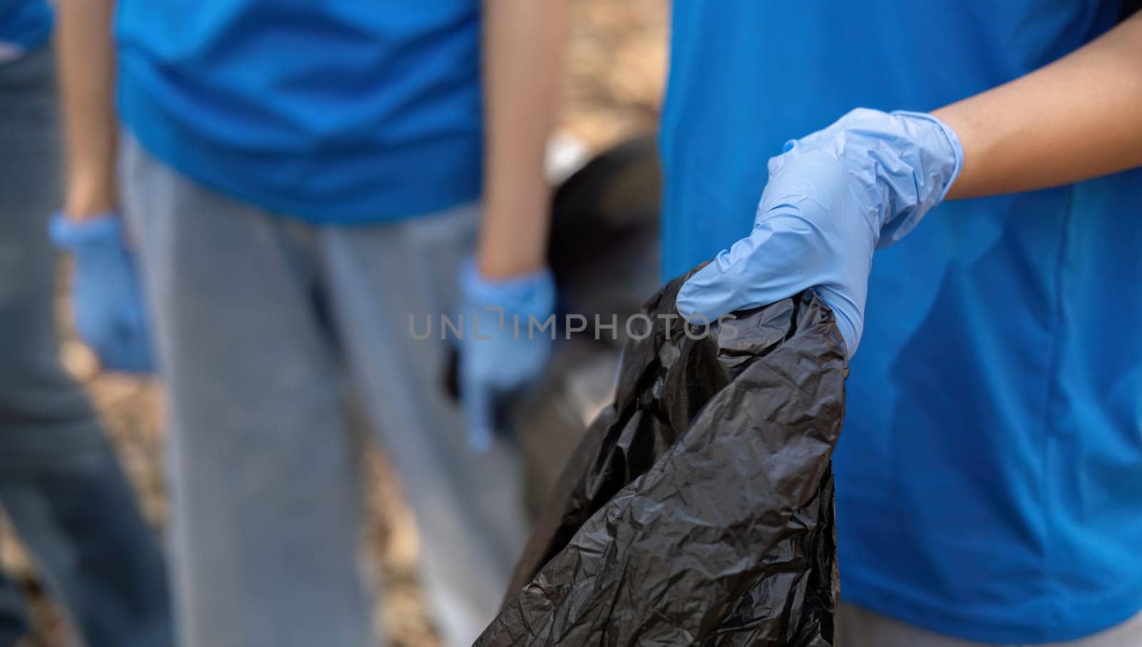 A group of Asian volunteers collects trash in plastic bags and cleaning areas in the forest to preserve the natural ecosystem..