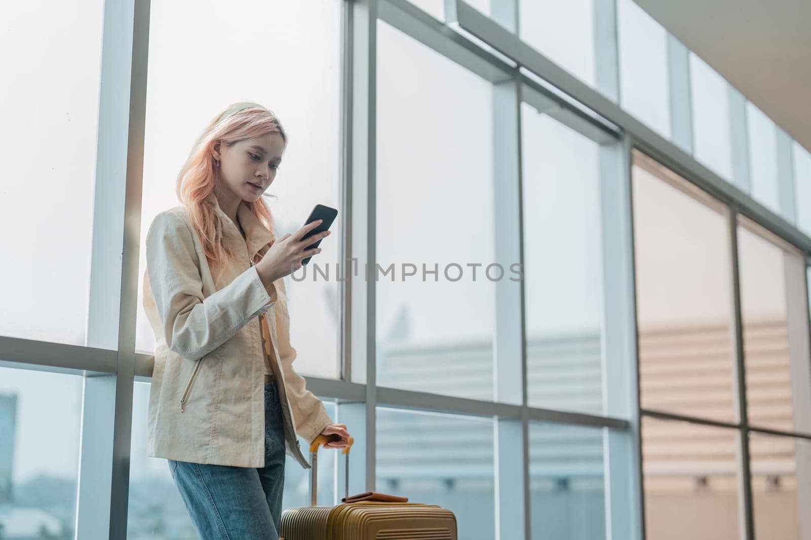 Traveler woman asian in airport and luggage for vacation, smile and holding the phone check boarding ticket. Female traveler with suitcase, international and departure with passport and trip.