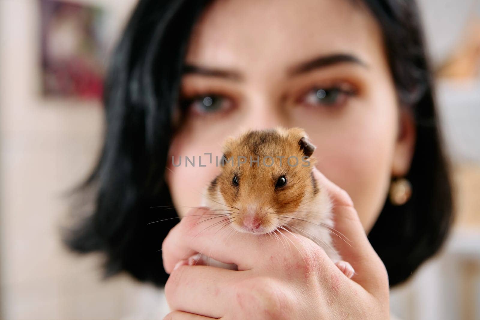 A black-haired woman enjoys a cozy day at home with her pet mouse, the two of them sharing a playful moment in the warm light of the living room.