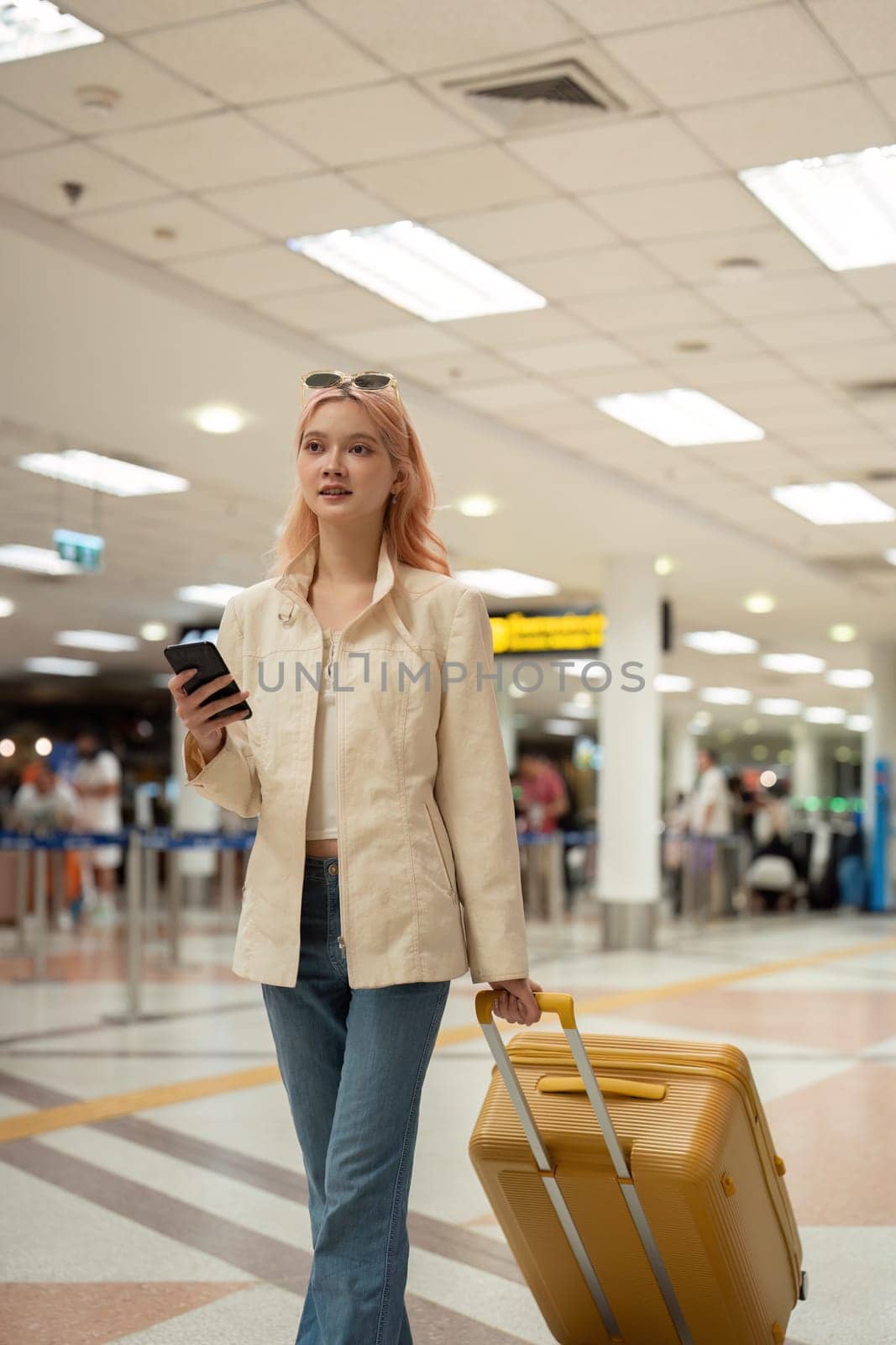 A woman asian walking in an airport. Mobile, suitcase and travel with a young female on an international trip for work or travel.
