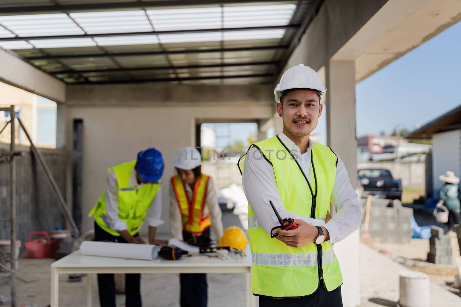 Two people are working on a blueprint, one of them is wearing a safety vest. Concept of collaboration and focus as the two individuals work together to create a detailed plan