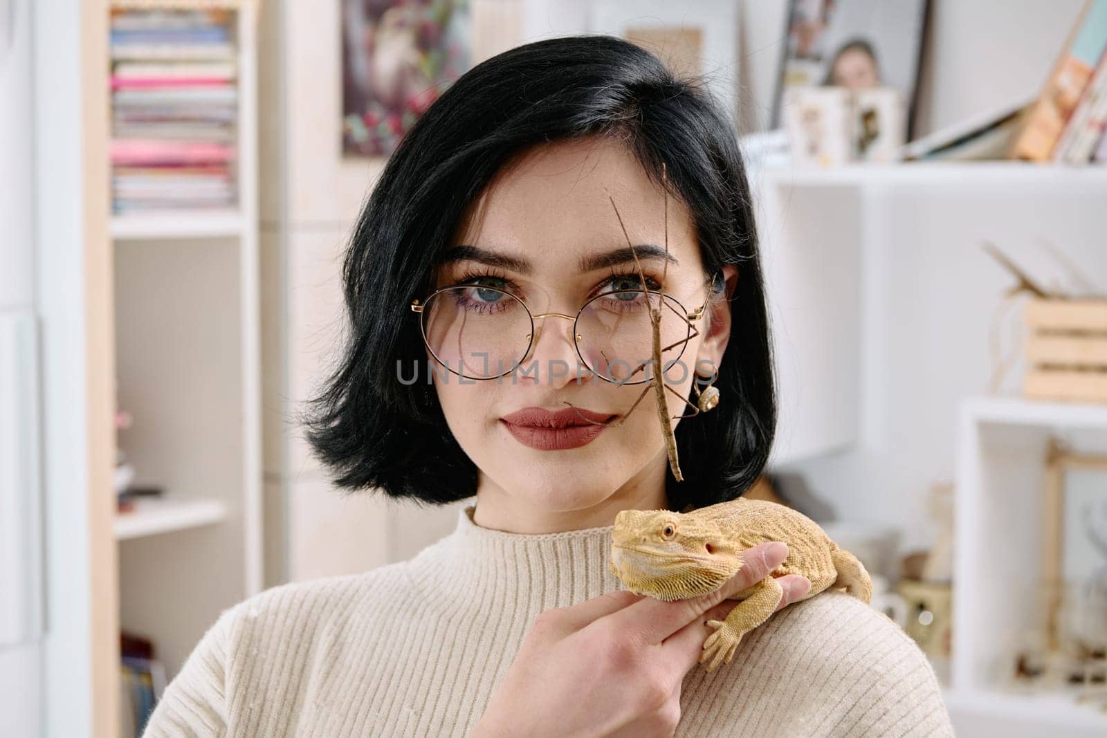 A young woman poses with her two pets, a bearded dragon and a stick insect, in this heartwarming photo.