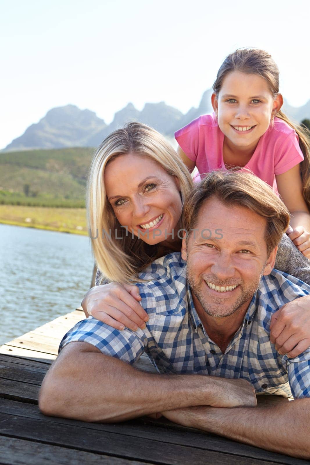 Smile, lake and portrait of family in nature for summer vacation, weekend trip and bonding together. Man, woman and relax with daughter outdoors for happiness, adventure and tourism travel in Europe.