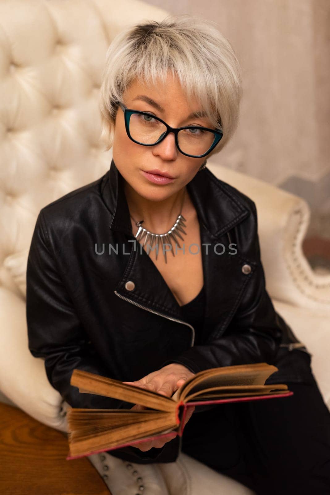 Portrait of an adult beautiful girl with glasses and short hair, holding a book in her hand in room