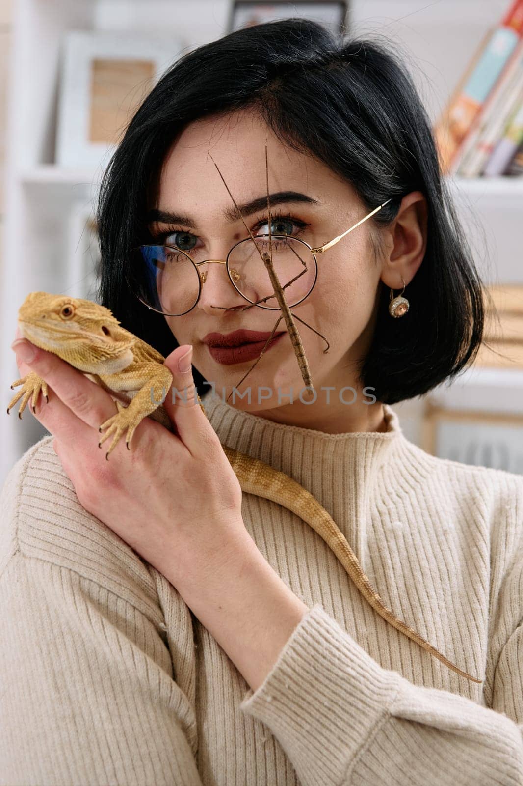 A young woman poses with her two pets, a bearded dragon and a stick insect, in this heartwarming photo.