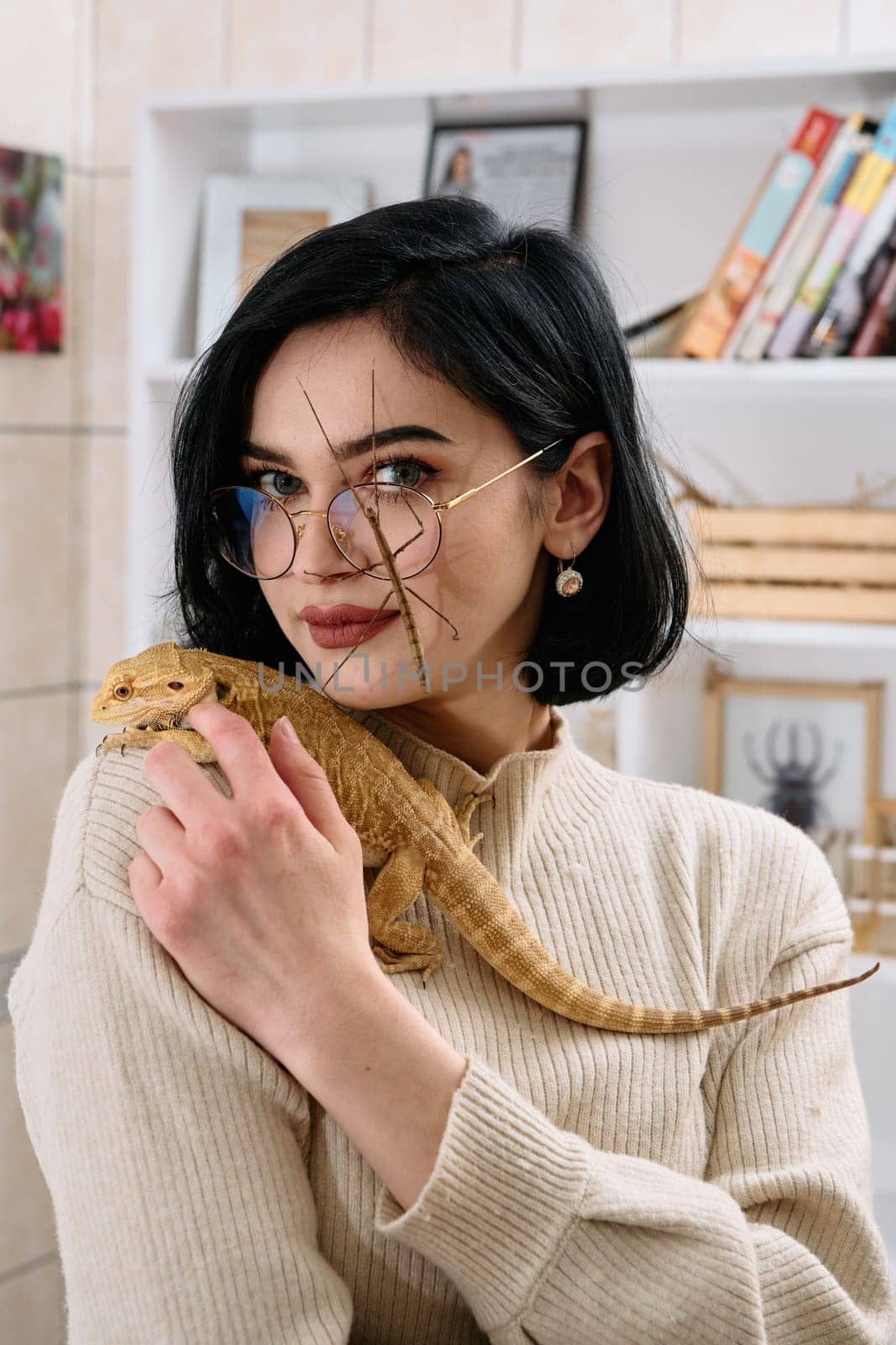 A young woman poses with her two pets, a bearded dragon and a stick insect, in this heartwarming photo.