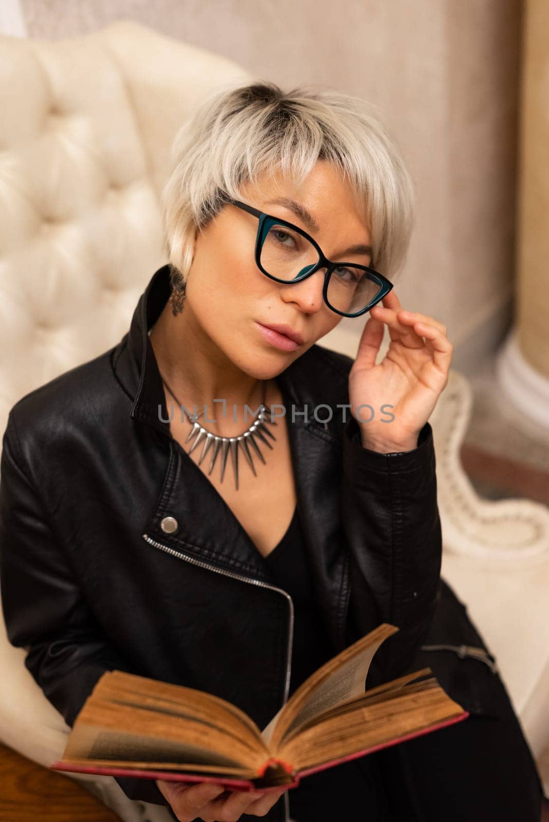 Portrait of an adult beautiful girl with glasses and short hair, holding a book in her hand in a room by Rotozey