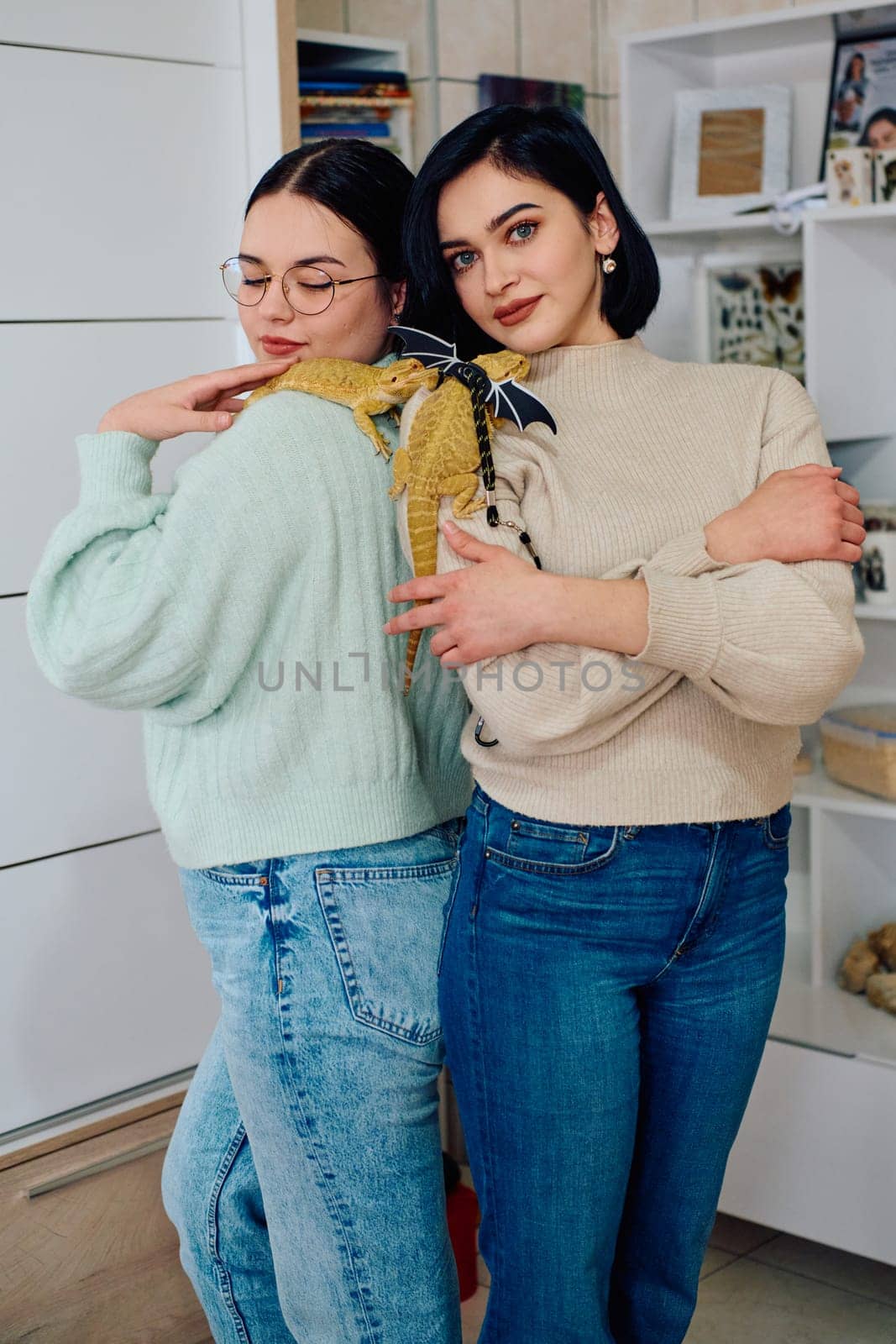 The sisters' smiles and the lizard's calm demeanor suggest that they are all enjoying each other's company.