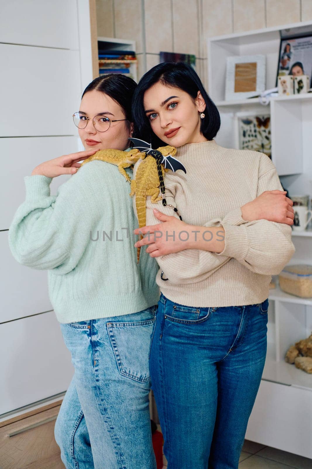 The sisters' smiles and the lizard's calm demeanor suggest that they are all enjoying each other's company.