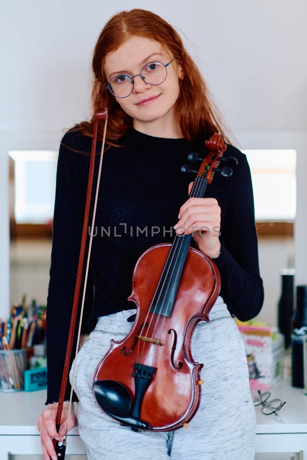 A stunning redhead musician exudes elegance as she poses with her violin, embodying both grace and musical prowess.