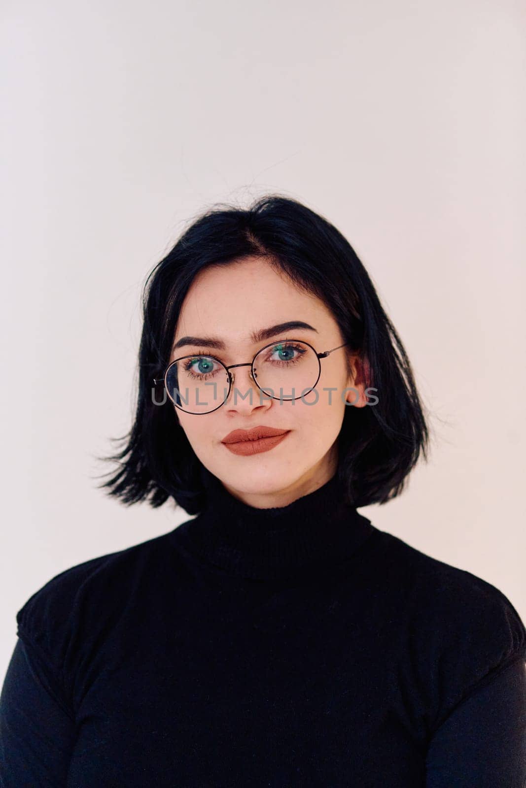 A brunette woman radiates joy as she proudly wears her eyeglasses, showcasing a warm smile against a clean white backdrop