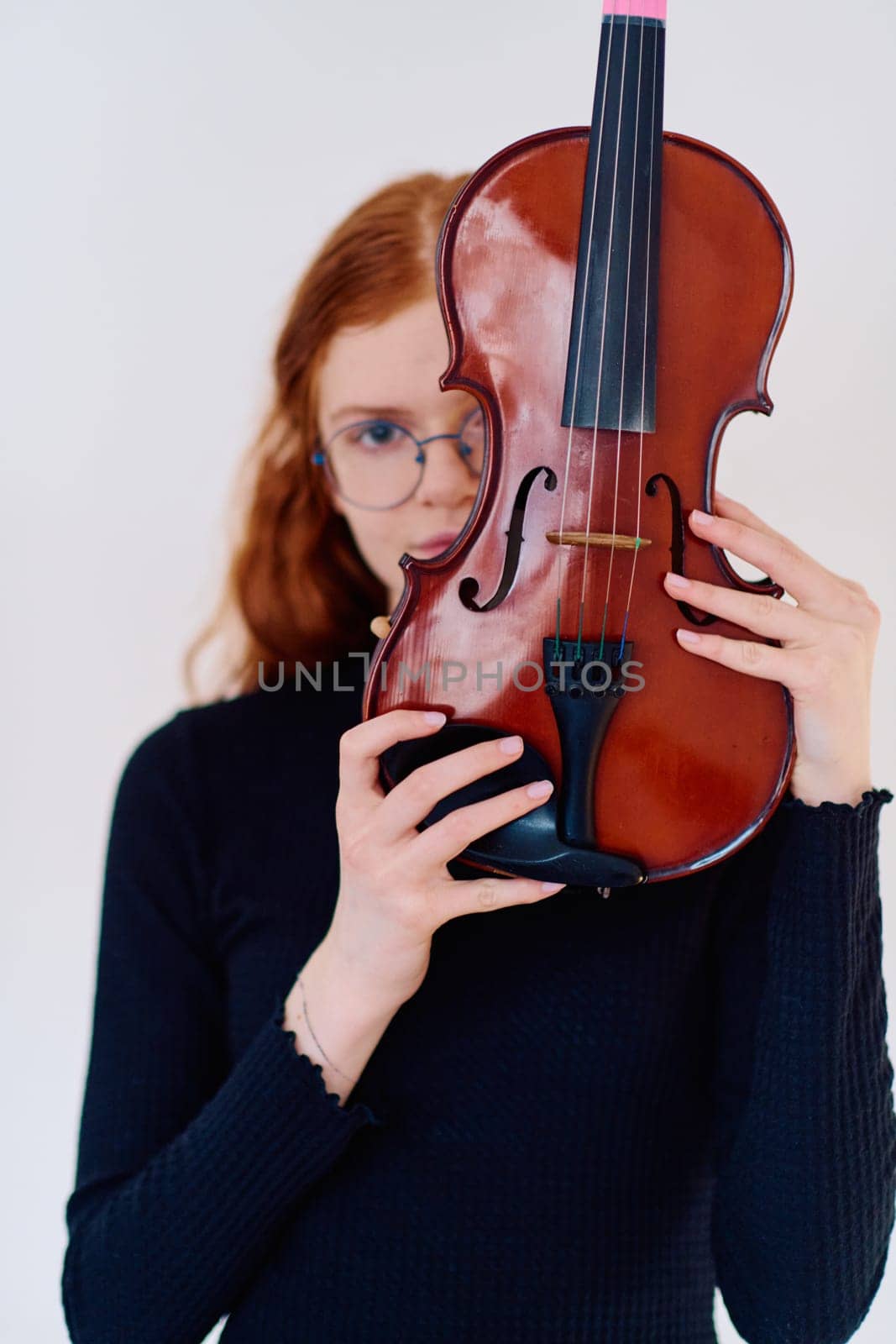 A stunning redhead musician exudes elegance as she poses with her violin, embodying both grace and musical prowess.