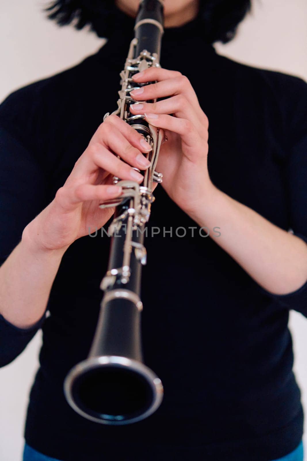 A talented brunette musician showcases her artistry as she gracefully holds and plays the clarinet against a pristine white background