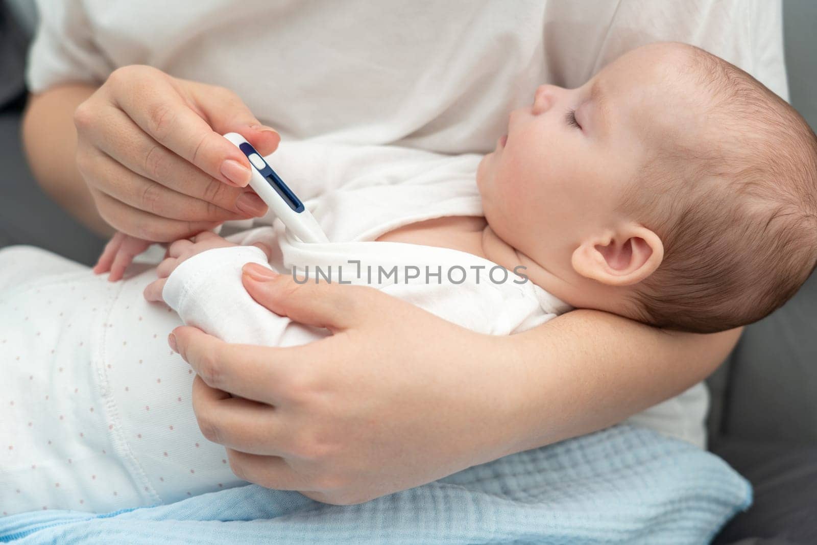 Mother uses an electronic thermometer to ascertain if her peacefully resting baby has a fever