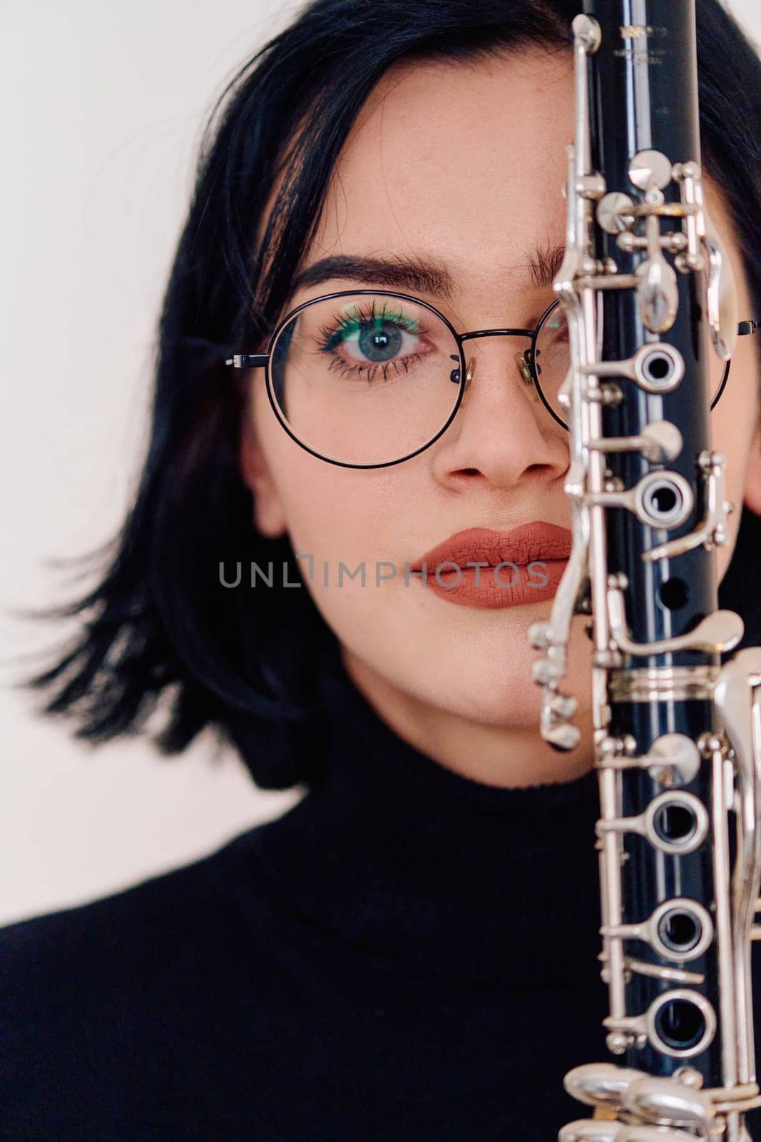 A talented brunette musician showcases her artistry as she gracefully holds and plays the clarinet against a pristine white background