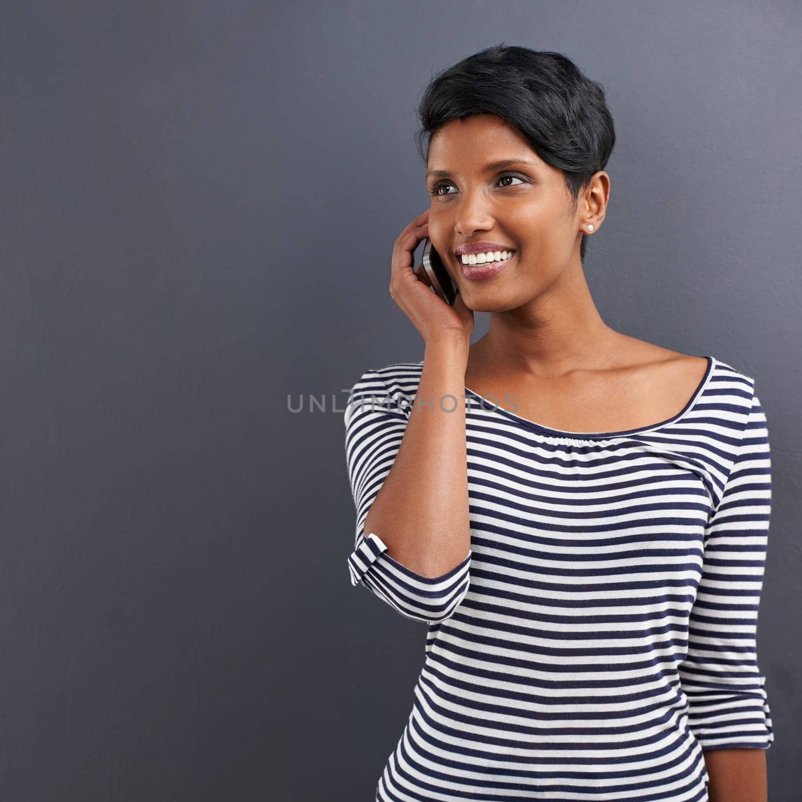 Happy woman, communication and discussion with phone for call on a gray studio background. Young female person with smile and talking on mobile smartphone for friendly conversation on mockup space.