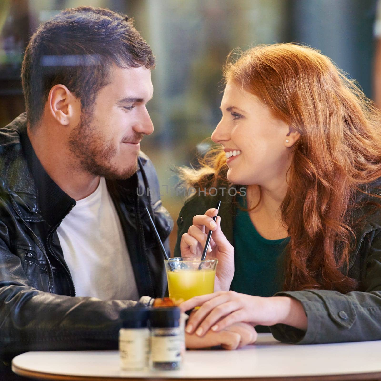 Couple, holding hands and juice in cafe happy with smile, romance and affection on anniversary date. Romantic, man and woman in restaurant bonding with drink or beverage and joy in relationship.