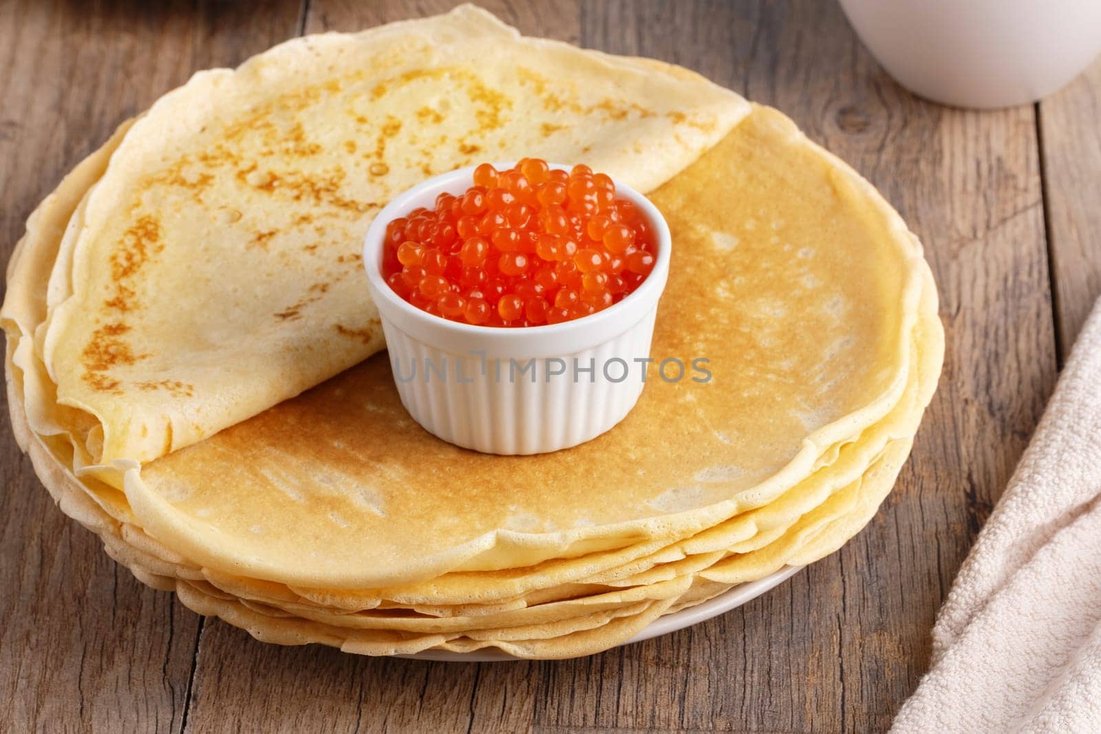 Pancakes with red caviar on a wooden table.