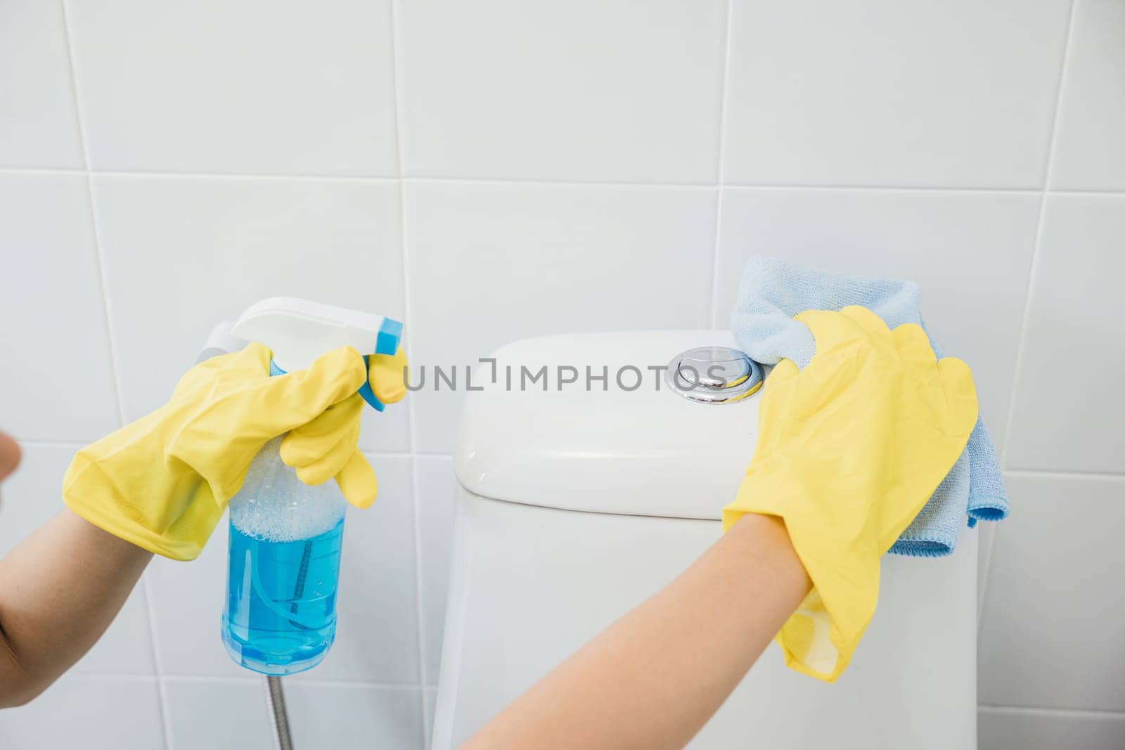 Maid in yellow gloves meticulously cleans the toilet seat in restroom using cloth. Her focus on purity and hygiene embodies the housekeeper dedication to bathroom care. Housekeeper healthcare concept