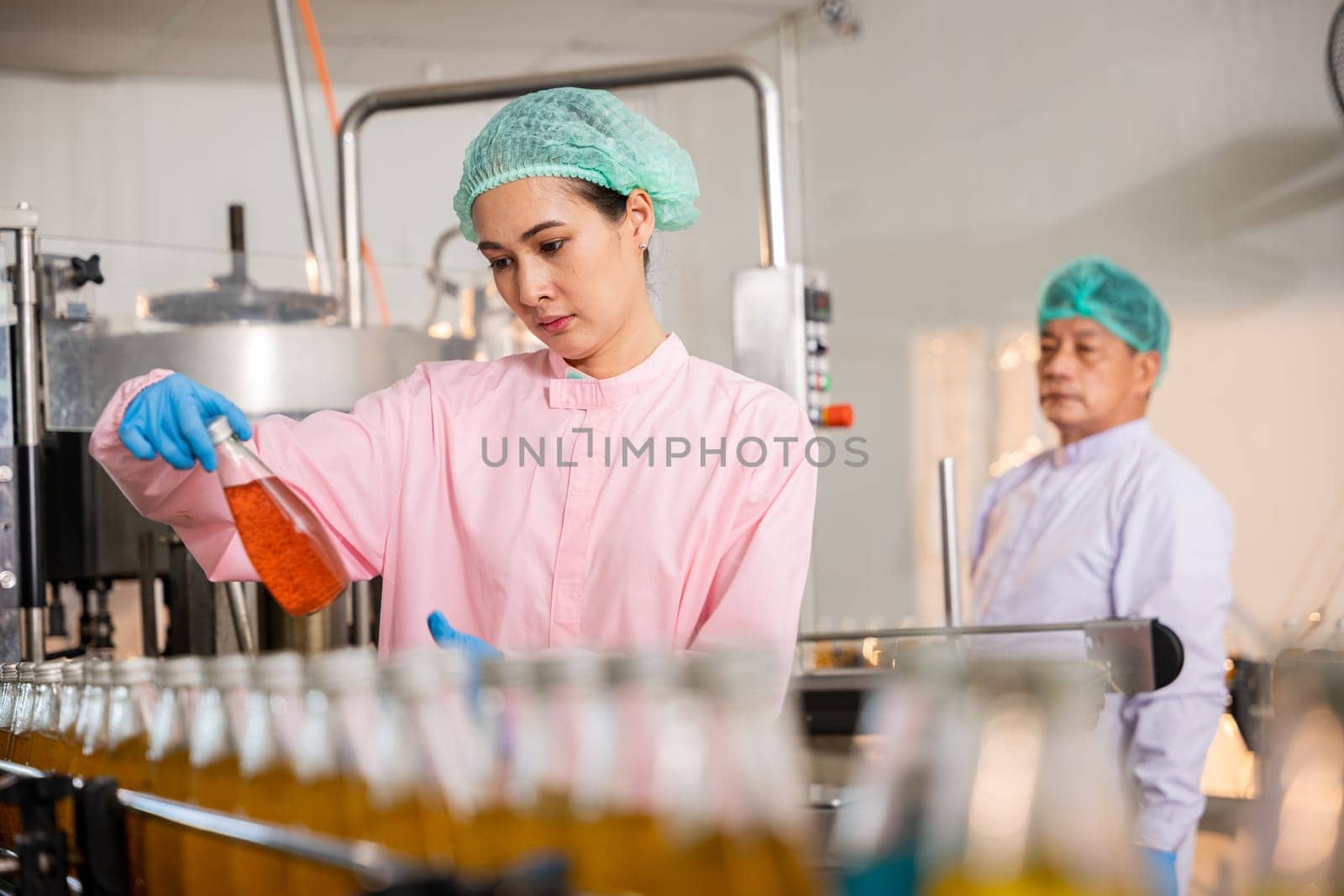 QC engineers inspect fruit juice drink production in glass bottles at the factory. Their careful examination ensures the highest quality and hygiene standards in manufacturing.