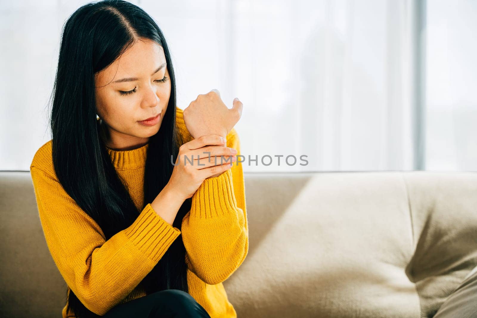 Woman holds her achy hand suggesting Carpal Tunnel Syndrome or discomfort by Sorapop