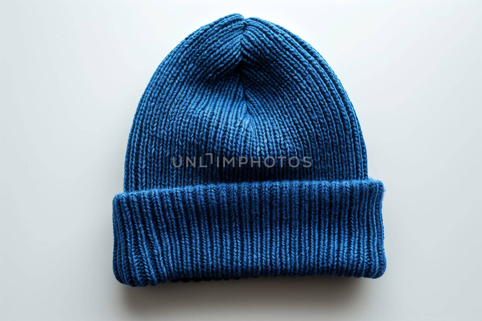 A blue knitted hat placed on a plain white background, showcasing the texture and color of the hat.