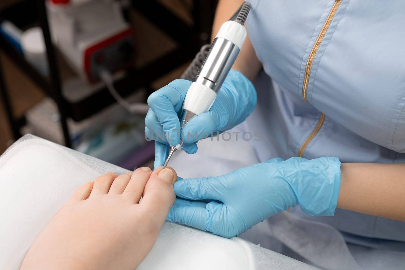 A pedicure master in the beauty salon employs an electric drill machine to perform a professional hardware pedicure.