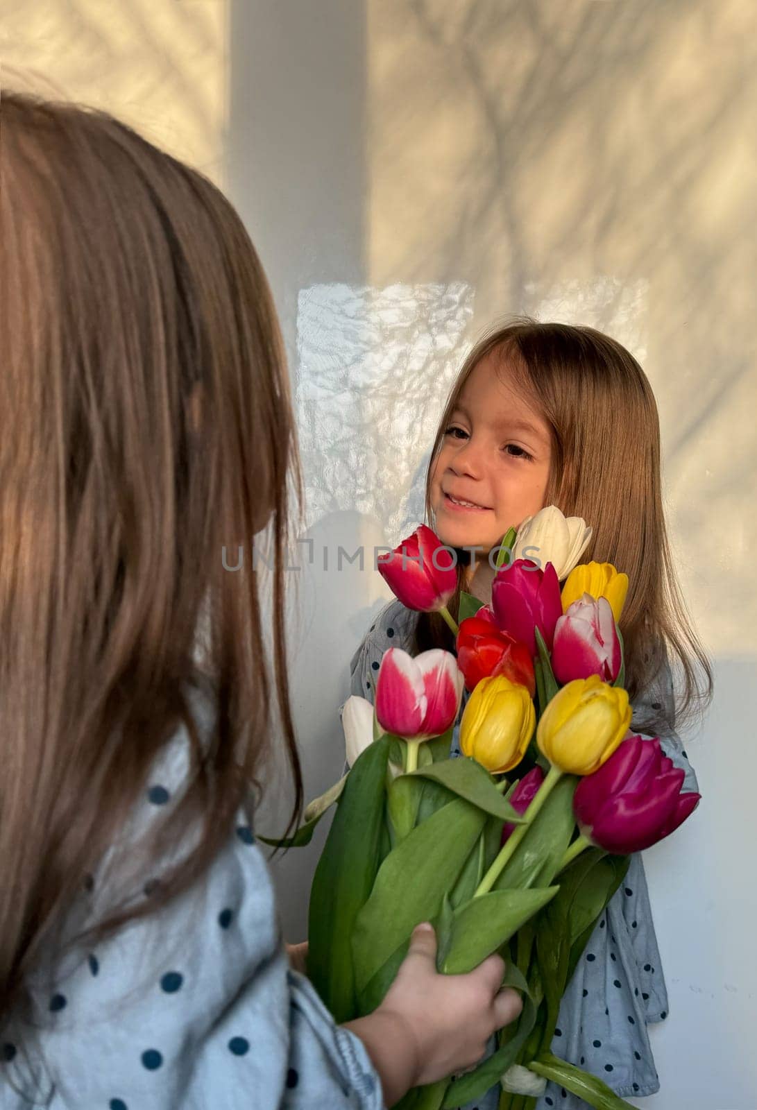 Siblings or twin day. Women's or Mother's Day. Portrait of two smiling little girl with a bouquet of tulips. Space for text