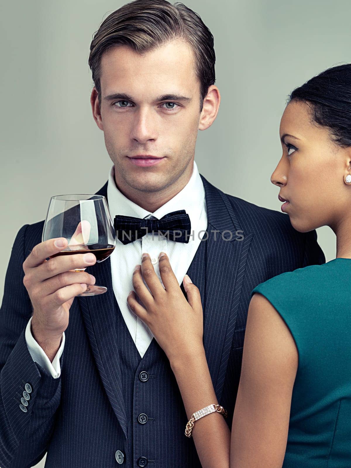 Alcohol, fashion and portrait of couple in studio with elegant, formal and stylish clothes for event. Luxury, party and man and woman with drink and confidence, pride and glamour on gray background.