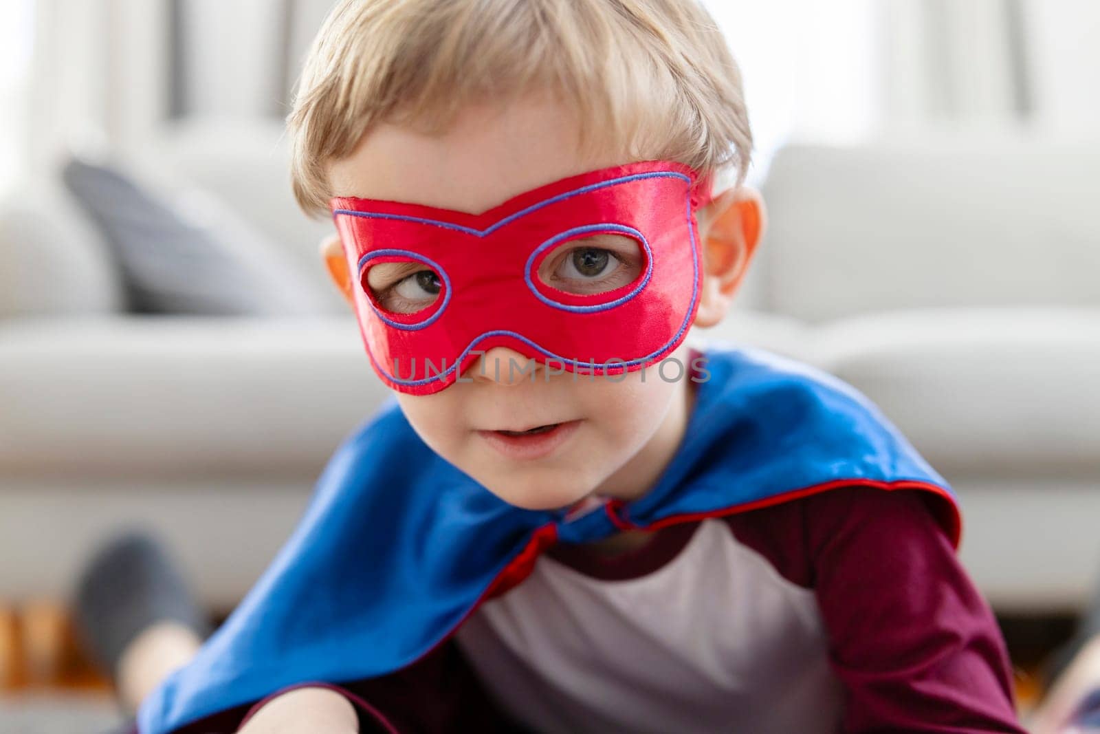 Close-up of a toddler boy dressed in a superhero costume with a mask, portraying strength and playfulness.