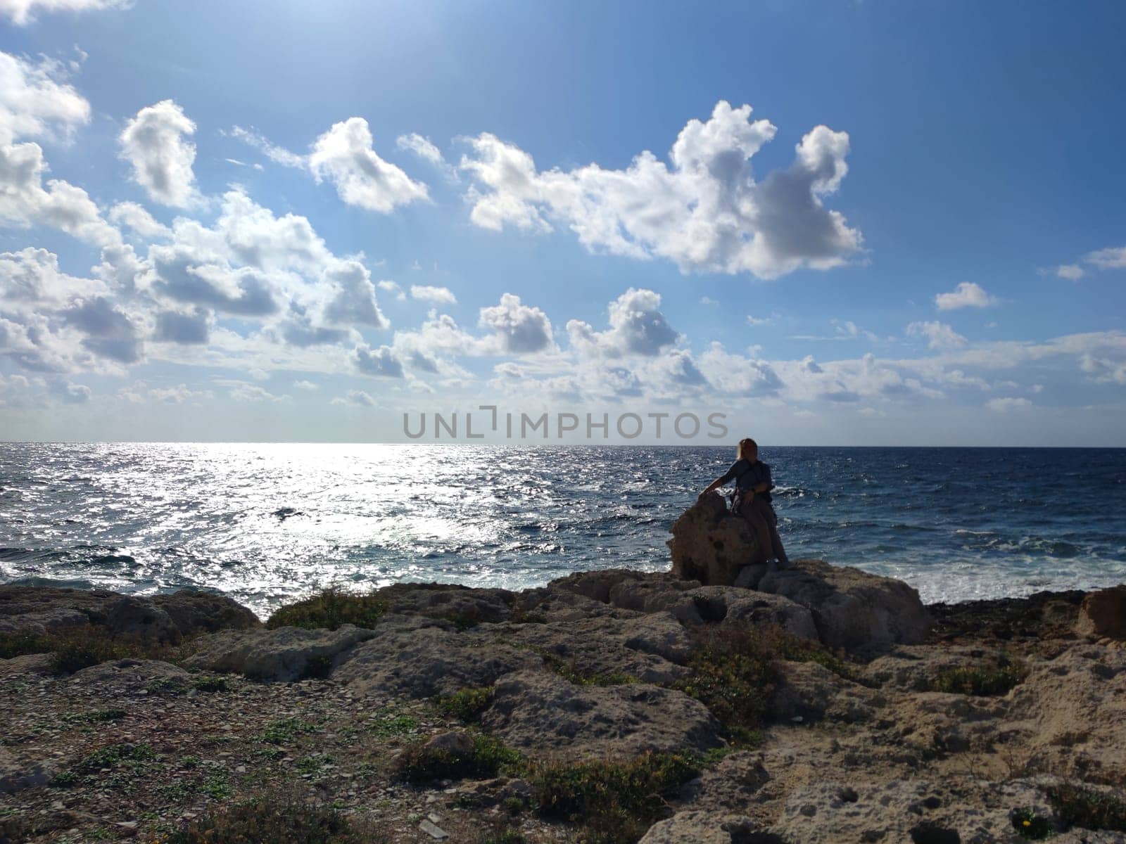 woman sitting on a stone by the sea, solo travel