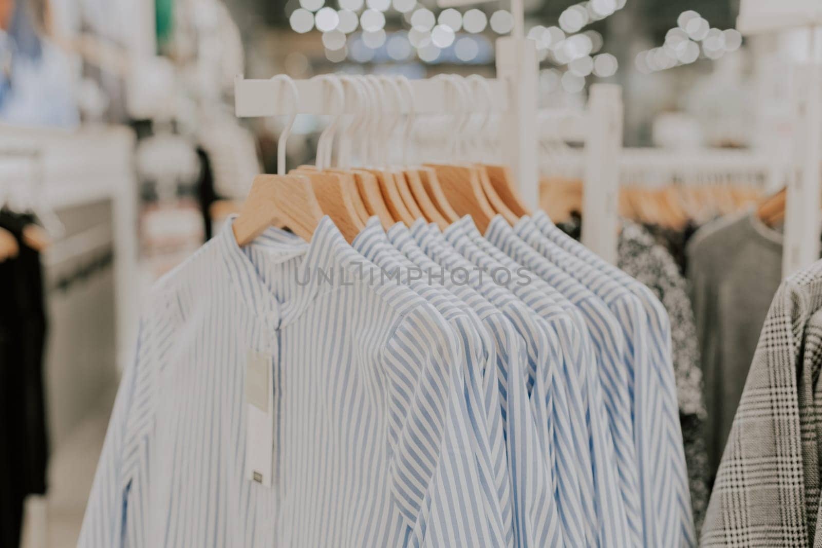 Women's blue and white striped shirts hanging on a hanger at a stand in a clothing boutique, during shopping discounts, close-up side view.