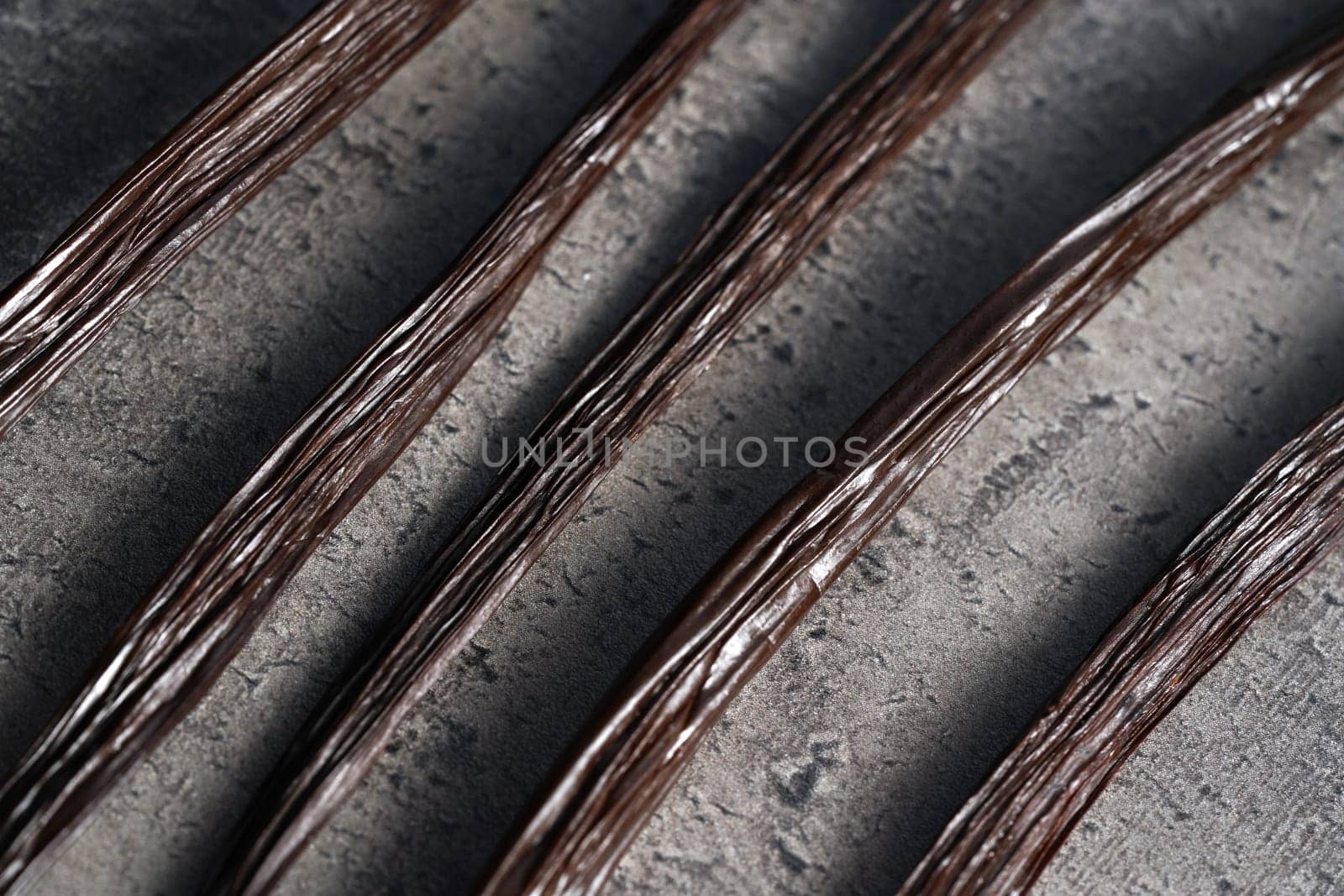 Brown vanilla beans, closeup photo on dark grey stone like kitchen desk