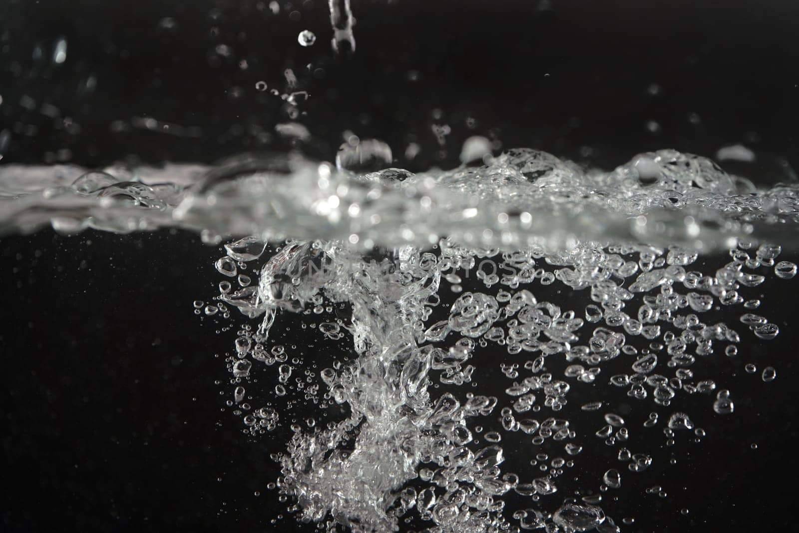 Water splashing as it's poured into aquarium tank, black background