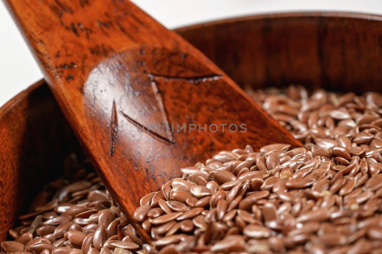 Common flax seeds in small wooden cup with spoon, closeup detail by Ivanko