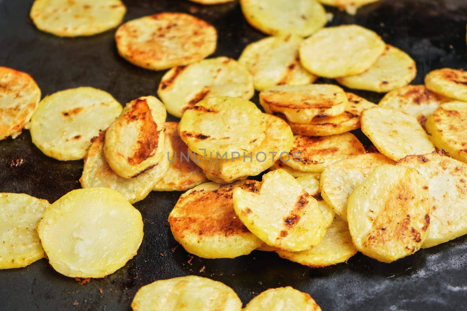 Potatoes cut to round chips grilled on electric grill, closeup detail on slices with brown burn marks