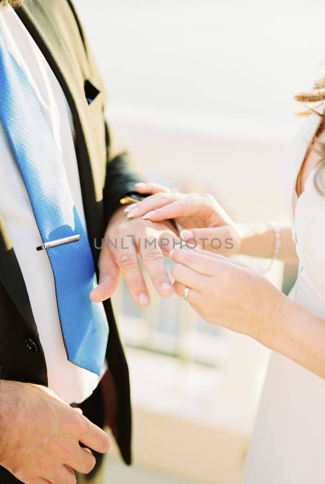 Bride puts the wedding ring on groom finger. Cropped. Faceless. High quality photo
