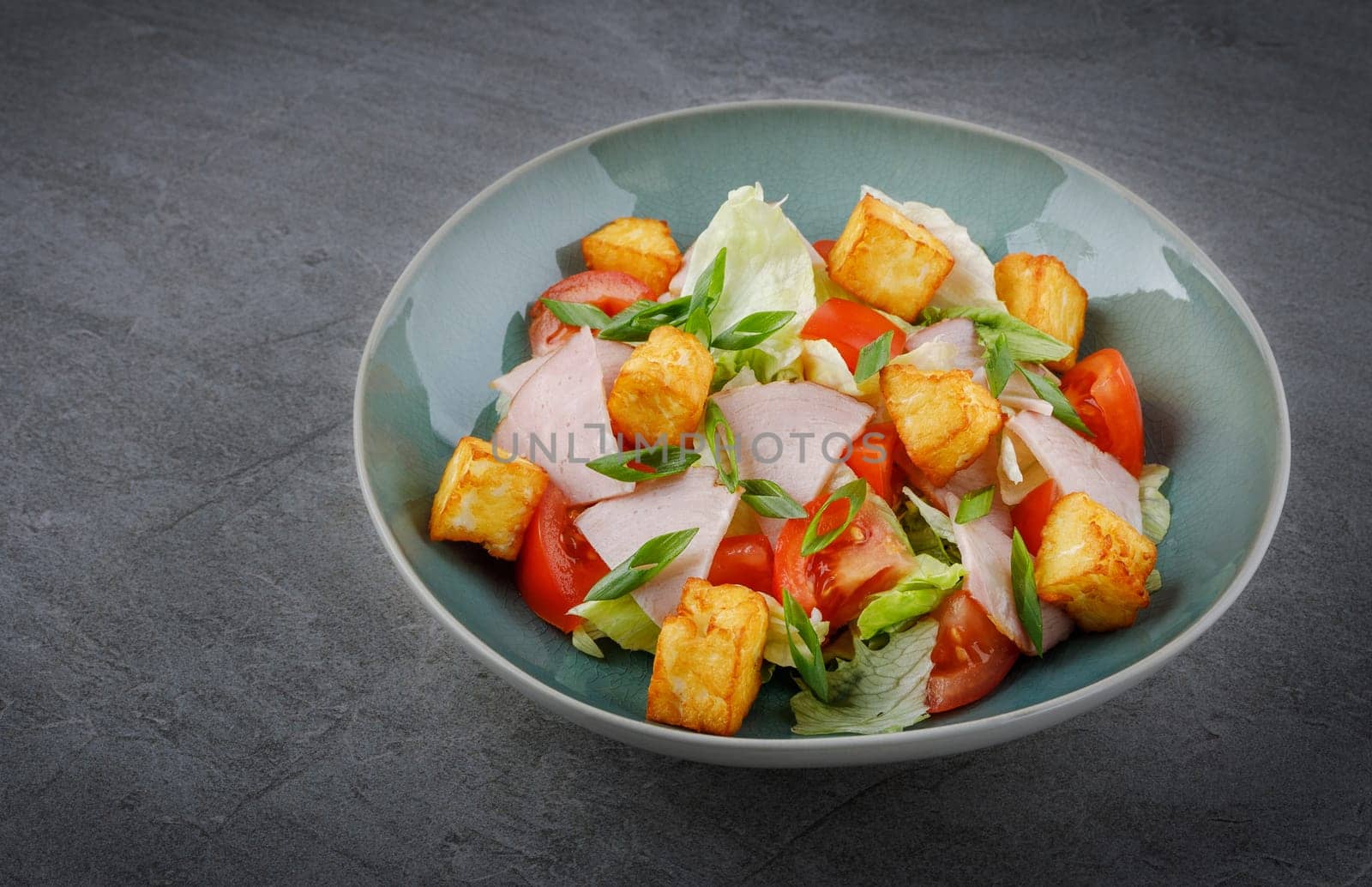 Close-up of salad with ham and halloumi cheese in a bowl on the table