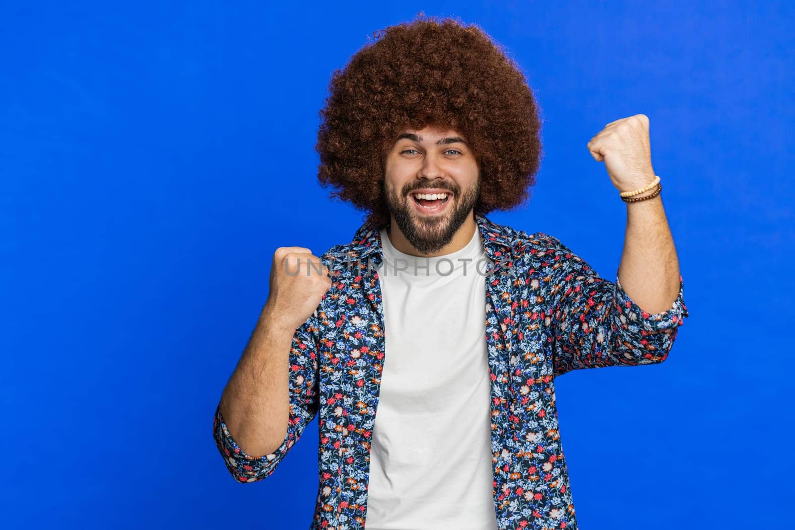 Happy cheerful Caucasian man celebrating success victory, winning birthday, lottery jackpot goal achievement play casino game good positive news triumph. Stylish guy isolated on blue studio background